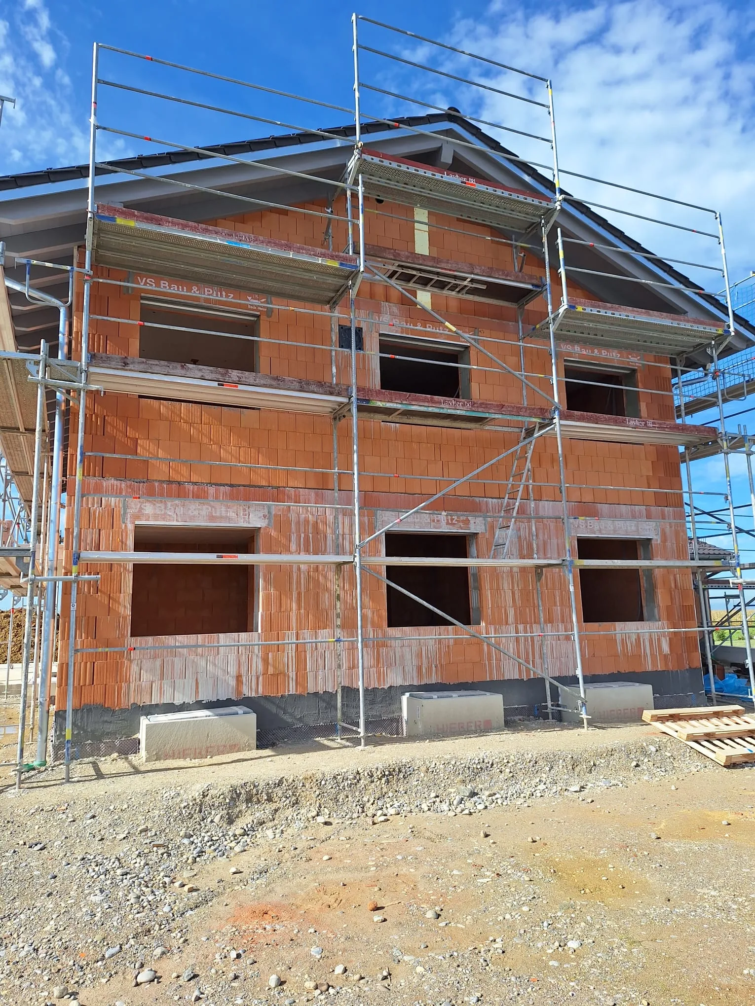 Ziegelrohbau mit Gerüst und vorbereiteter Dachkonstruktion