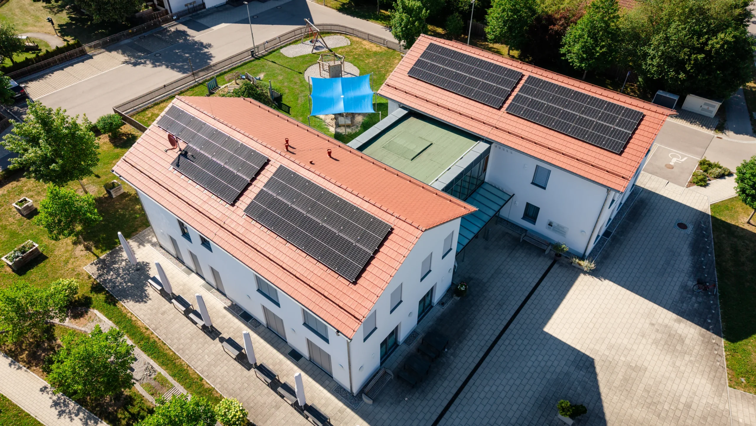 Dorfgemeinschaftshaus Rammingen mit zwei Gebäudeflügeln und Photovoltaikanlage aus der Luft