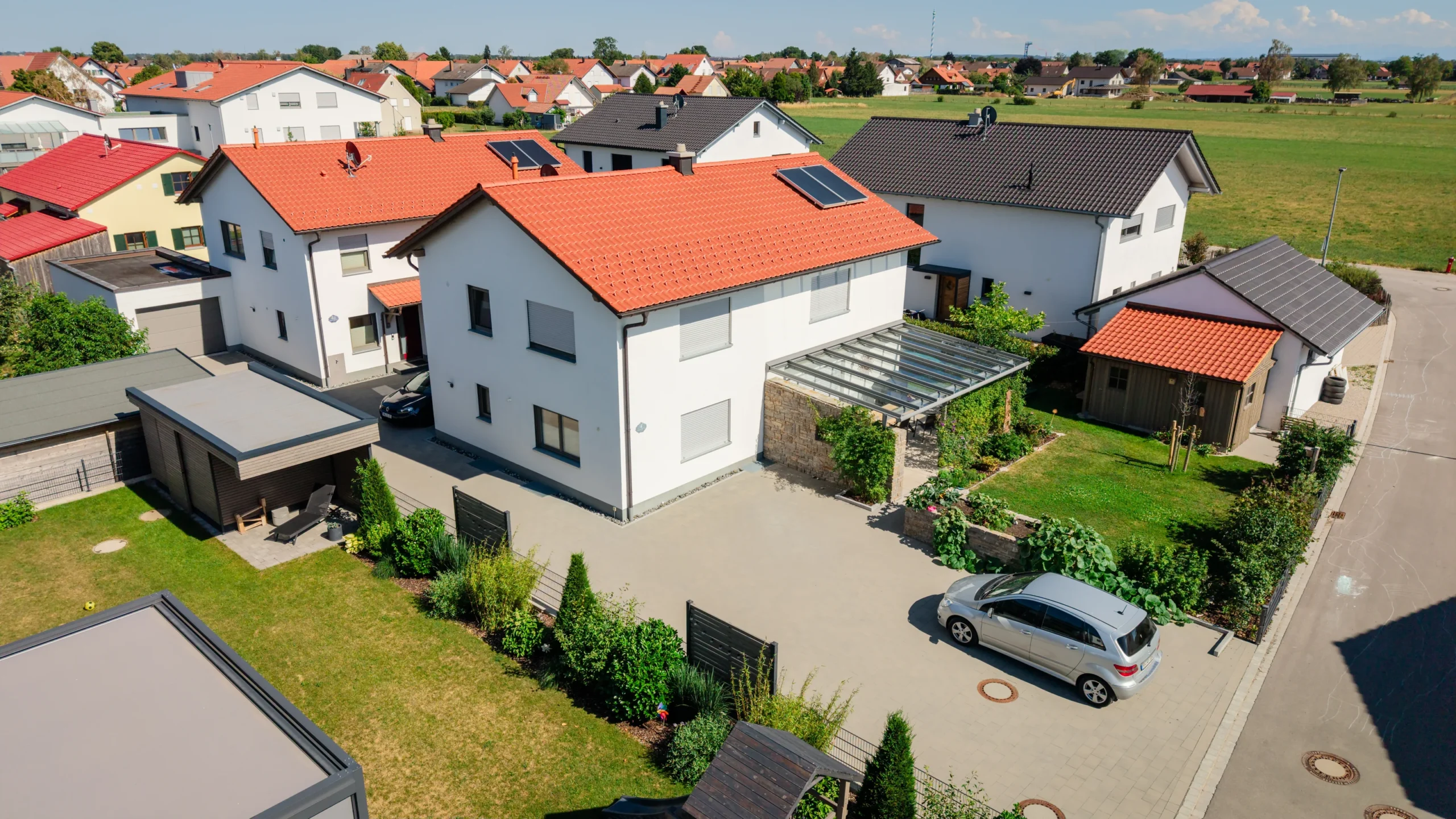 Zwei hintereinander stehende Einzelhäuser in Rammingen mit Zufahrt und umliegender Wohnbebauung aus der Luft